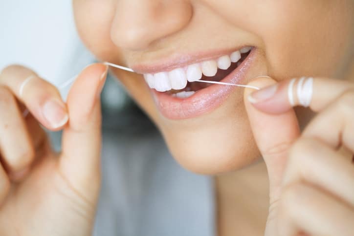 close-up of beautiful smiling woman with dental floss